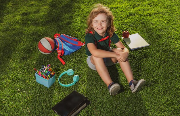 Niño pequeño aprendiendo al aire libre estudiando en línea y trabajando en tableta en campo verde