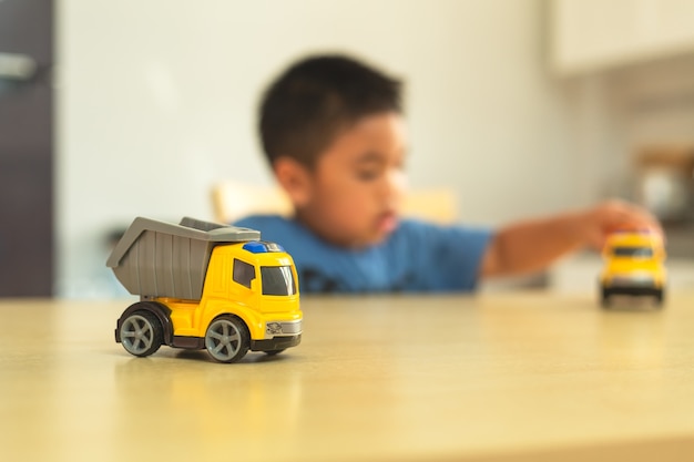 El niño pequeño asiático está jugando con los coches de juguete en casa