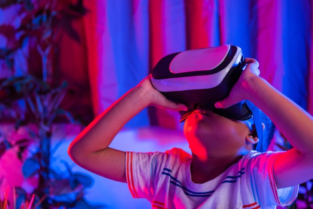 Niño pequeño asiático con gafas de realidad virtual experimentando la realidad