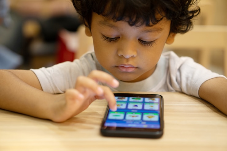 Foto el niño pequeño asiático lindo está jugando a un juego en smartphone