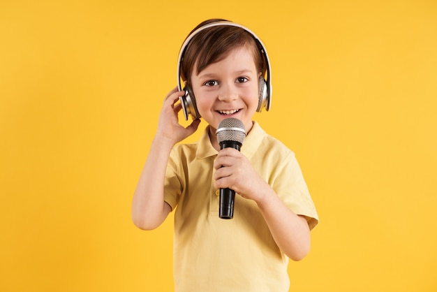 Foto el niño pequeño en auriculares canta en el karaoke.