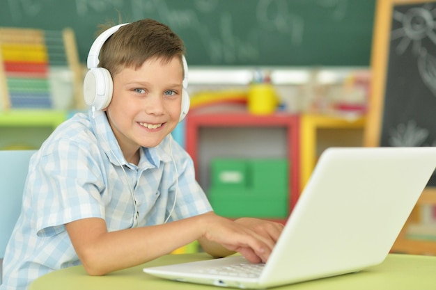 Niño pequeño con auriculares usando una computadora portátil en el aula