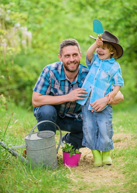 niño pequeño ayuda al padre en la agricultura. regadera, olla y azada. Equipo de jardín. padre e hijo con sombrero de vaquero en el rancho. feliz día de la Tierra. Vivero de árboles genealógicos. Granja ecológica. Jardinero apuesto.