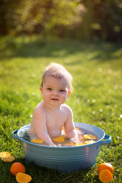 Niño pequeño se baña en el parque con naranjas