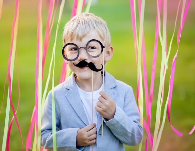 Niño pequeño con bigote de papel divertido y gafas