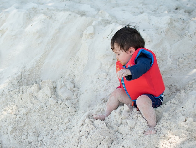 Niño pequeño caer de la arena en la playa