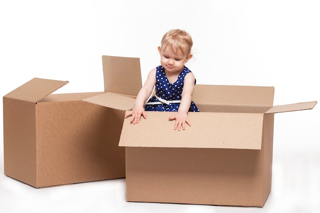 Un niño pequeño en cajas de cartón sobre superficie blanca