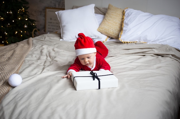 Niño pequeño con cajas de regalo en la cama en su casa