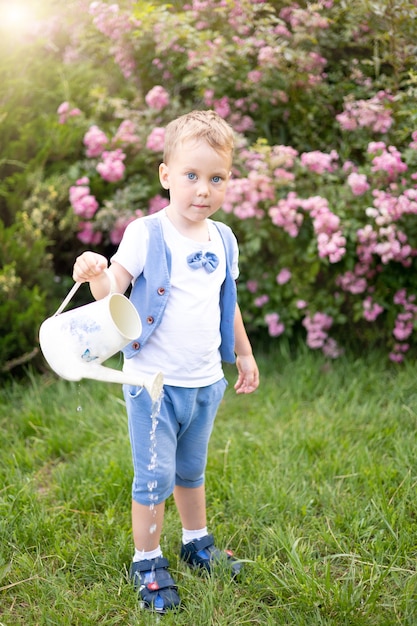 Un niño pequeño camina por un campo de margaritas sostiene una canasta de flores en sus manos sonríe