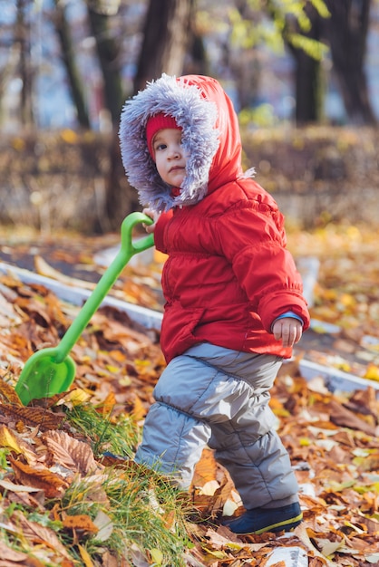 Niño pequeño camina en el parque con una pala