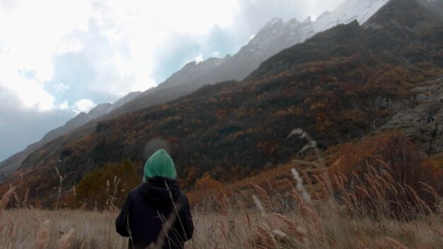 Un niño pequeño camina por el sendero hacia las montañas, un niño creativo en una caminata con ropa abrigada