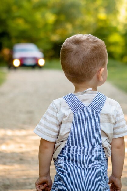 Un niño pequeño en un camino en el bosque. Peligro en el camino. El niño corre peligro en la carretera.