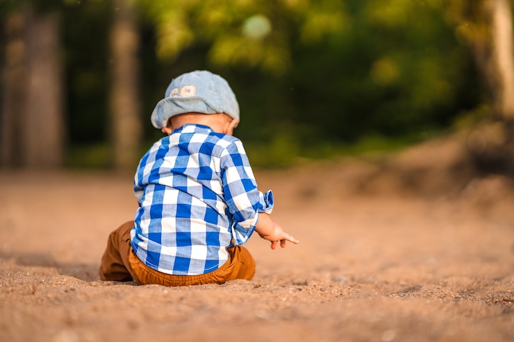 Foto un niño pequeño con una camisa azul juega con piedras y conchas en la playa