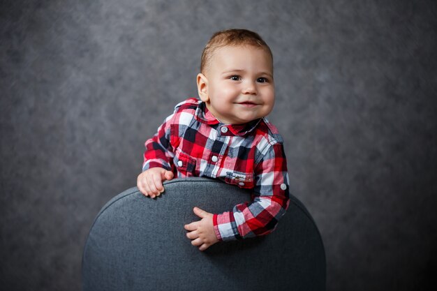 Foto niño pequeño en camisa sobre fondo gris sonríe maravillosamente