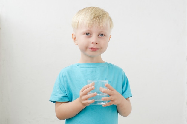 niño pequeño en una camiseta azul bebe agua