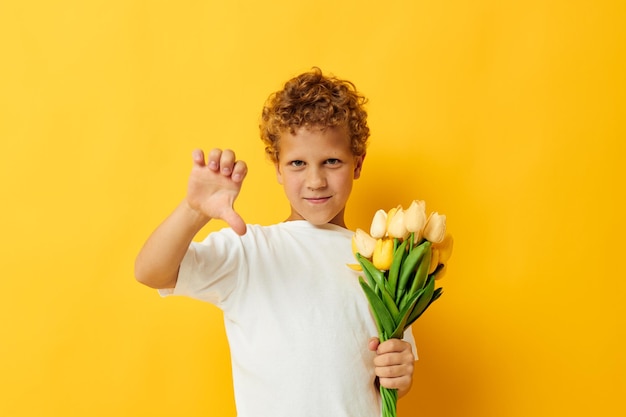 Niño pequeño en una camiseta blanca con un ramo de flores estudio aislado fondo inalterado