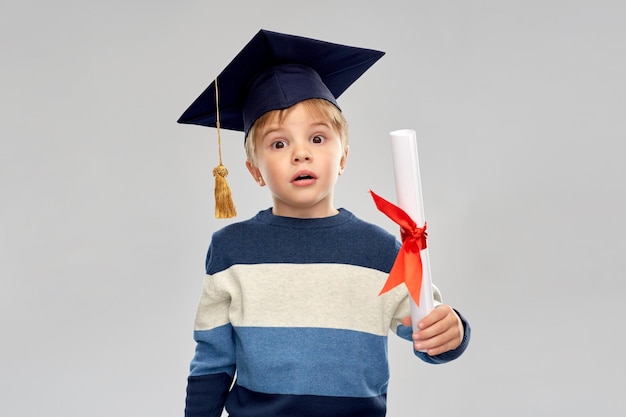 Niño pequeño en cartón de mortero con diploma