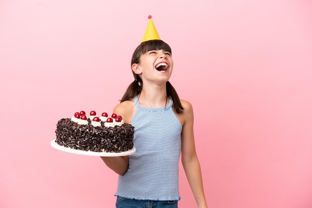 Niño pequeño caucásico sosteniendo pastel de cumpleaños aislado en fondo rosa riendo