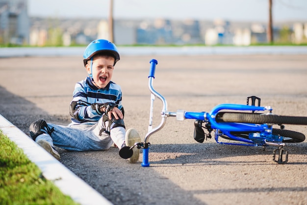 Un niño pequeño cayó de una bicicleta a la carretera, llorando y gritando de dolor.