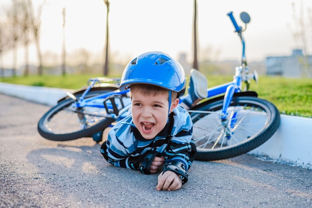 Un niño pequeño cayó de una bicicleta a la carretera, llorando y gritando de dolor.