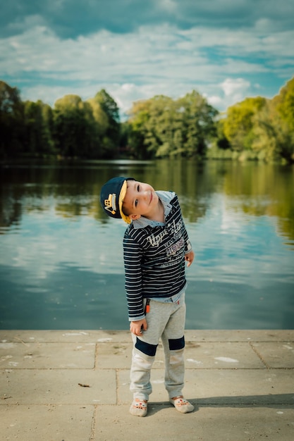 Un niño pequeño se para cerca de un lago en un parque en verano