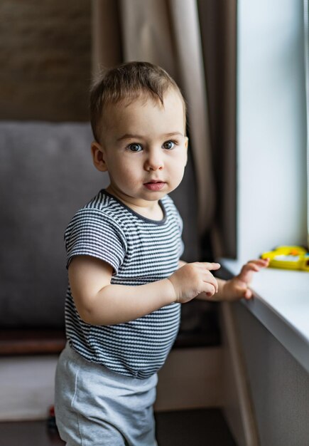 Foto un niño pequeño está cerca de la ventana y juega con un juguete.