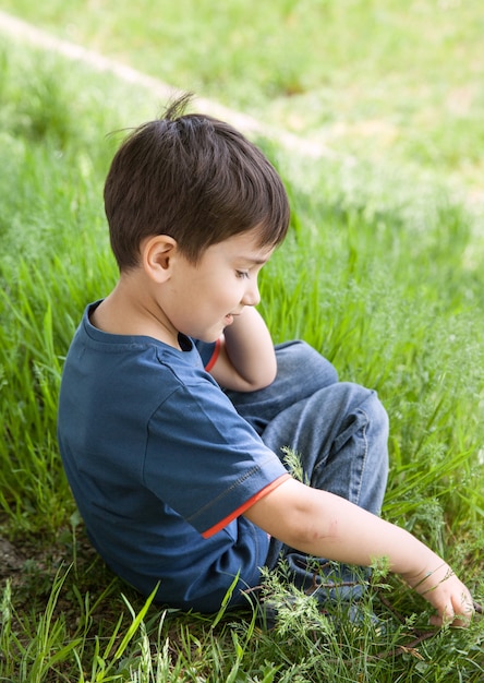 Foto niño pequeño en el césped entre hierba verde