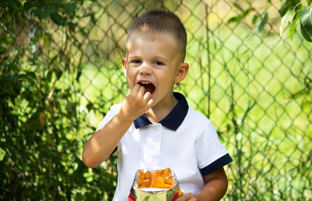 El niño pequeño come papas fritas.