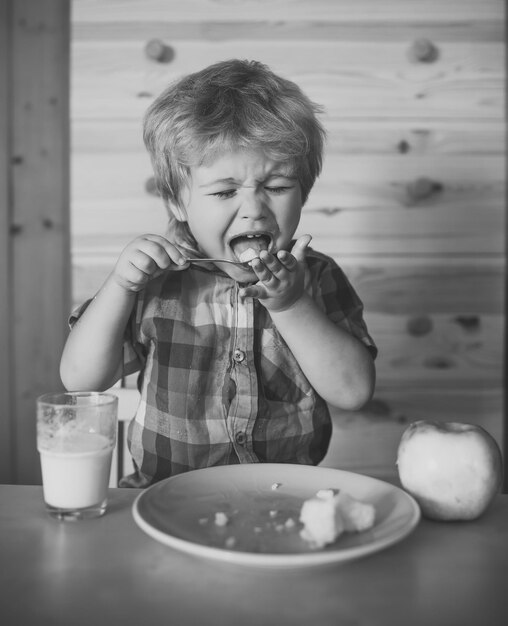 Niño pequeño come plátano y bebe leche