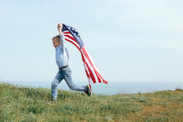 Un niño pequeño corre con la bandera de los Estados Unidos. 4 de julio Día de la Independencia.