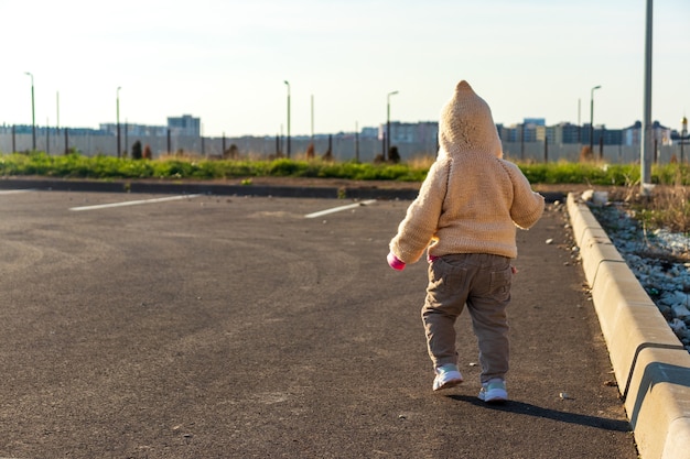 Un niño pequeño corre en el estacionamiento contra el sol poniente