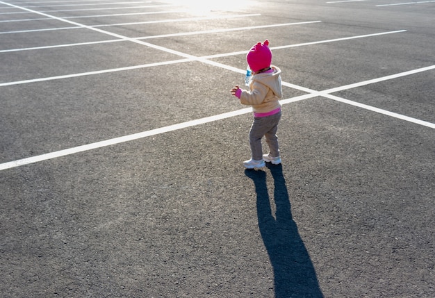 Un niño pequeño corre en el estacionamiento contra el sol poniente