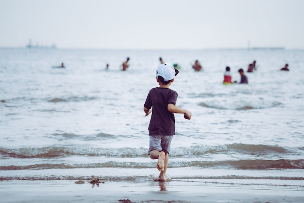 Niño pequeño corriendo a una playa de arena