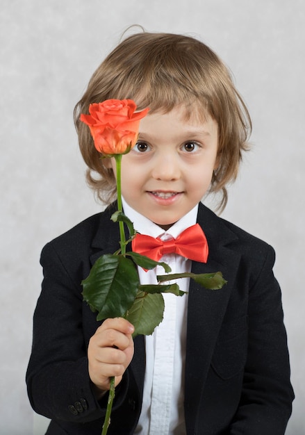 Niño pequeño de cuatro años con una rosa. De cerca