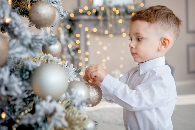 Niño pequeño decora un árbol de Navidad para Navidad