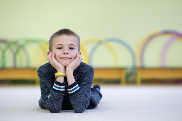 Niño pequeño descansando en el piso dentro de la sala de deportes