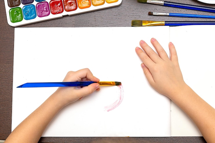 Foto niño pequeño dibuja con lápices de colores pastel en la mesa blanca día del padre