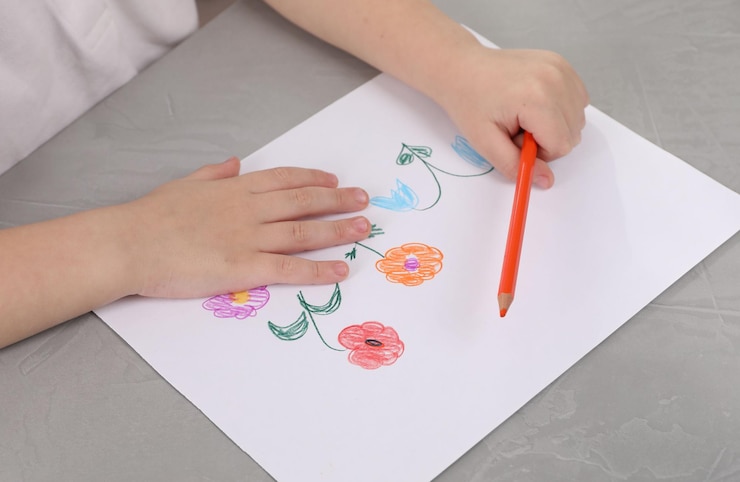 Foto niño pequeño dibujando flores con lápiz en una mesa de textura gris de primer plano arte de childs