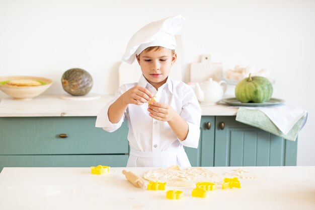 Niño pequeño en el disfraz de cocinero horneando galletas