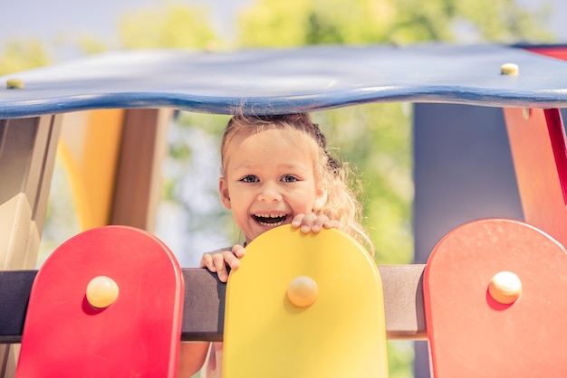 Niño pequeño divertido de pie en la casa de juegos de colores