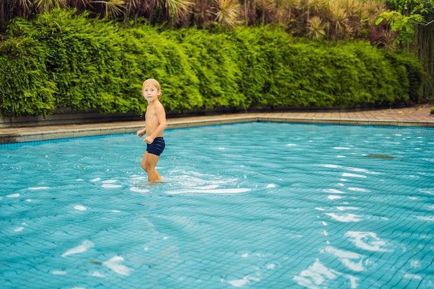 Niño pequeño divirtiéndose corriendo en la piscina