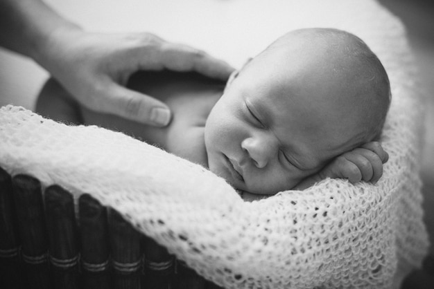 Foto un niño pequeño, de dos semanas, duerme en una canasta sobre una manta de lana