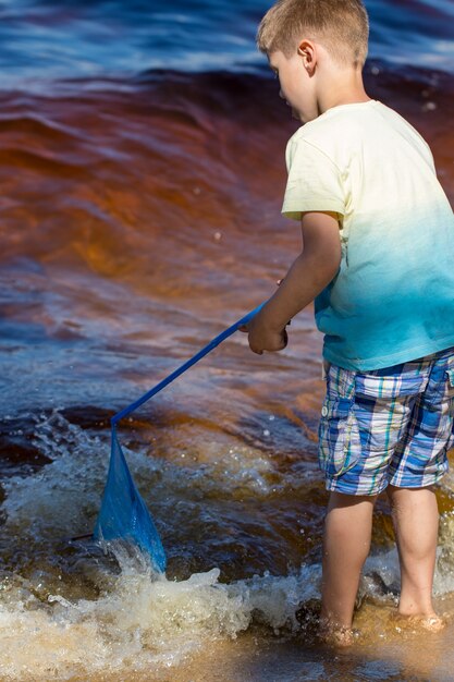 Niño pequeño se encuentra con una red de pesca directamente en el mar.