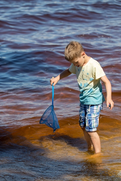 Niño pequeño se encuentra con una red de pesca directamente en el mar.