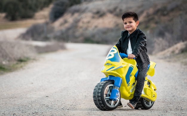 Foto niño pequeño, equitación, en, motocicleta, juguete