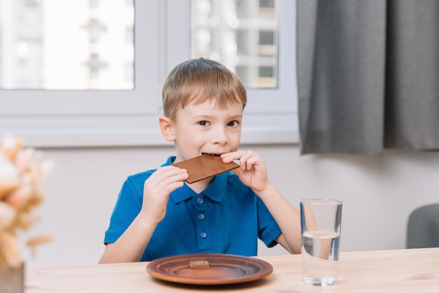 El niño pequeño era codicioso y comenzó a comer una gran barra de chocolate.