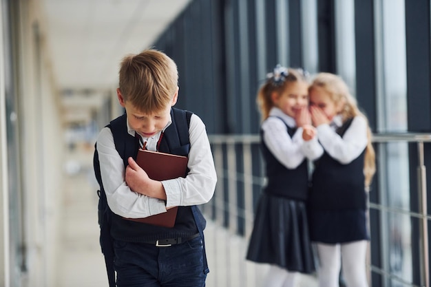 Niño pequeño es intimidado Concepción de acoso Niños de la escuela en uniforme juntos en el pasillo