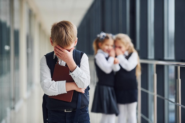 Niño pequeño es intimidado Concepción de acoso Niños de la escuela en uniforme juntos en el pasillo