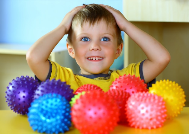 Niño pequeño está jugando con bolas de colores