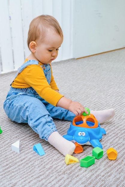 Un niño pequeño está jugando con un clasificador de juguetes sentado en el suelo.